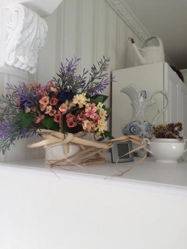 a bouquet of flowers on a shelf with a vase at House in Lviv in Lviv