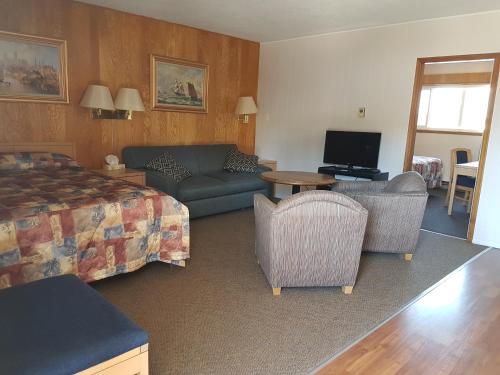 ein Hotelzimmer mit einem Bett, einem Sofa und Stühlen in der Unterkunft A-1 Alberni Inn in Port Alberni