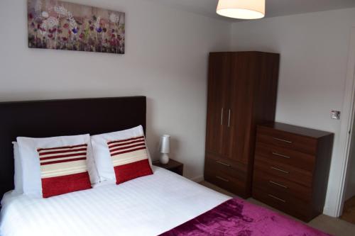 a bedroom with a bed with red and white pillows at Sky Night Serviced Apartments in Cardiff