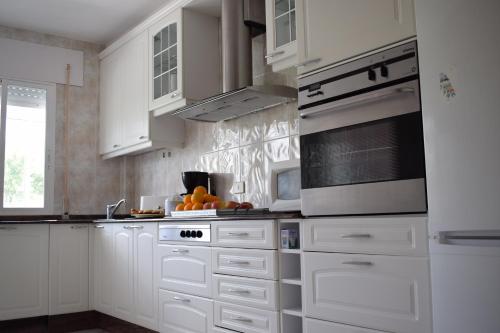 La cuisine est équipée de placards blancs et d'un four avec plaques de cuisson. dans l'établissement La Casa de Manuel, à Portomarín