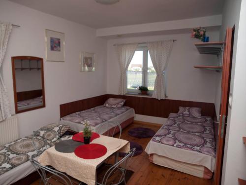 ラシンにあるPokoje Gościnne "Amelia"のベッド2台、テーブル、窓が備わる客室です。