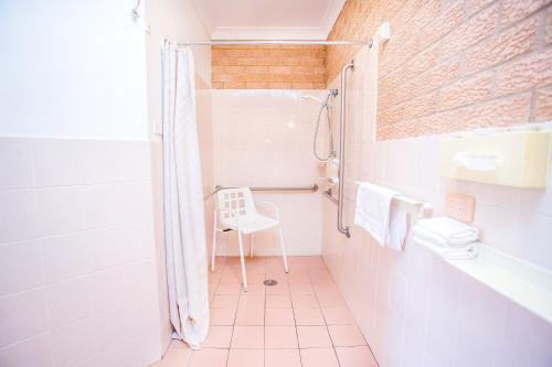a white bathroom with a shower and a toilet at Golden Chain Aalana Motor Inn in Cowra