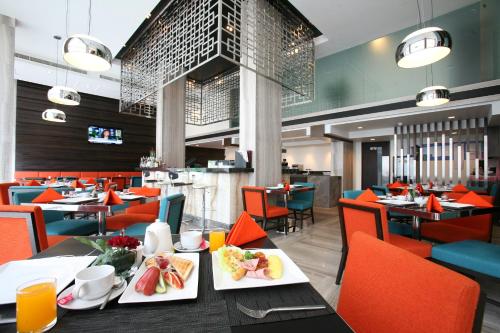 un restaurante con sillas naranjas y mesas con platos de comida en FX Hotel Metrolink Makkasan, en Bangkok