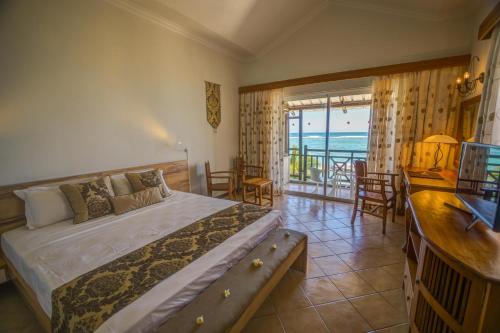 a bedroom with a bed and a balcony with the ocean at Le Peninsula Bay Beach Resort & Spa in Blue Bay