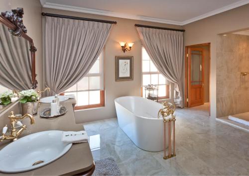 a bathroom with a large tub and a sink at La Plume Boutique Hotel & Spa in Oudtshoorn