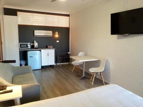 a living room with a table and a kitchen with a couch at Kurri Motor Inn in Kurri Kurri