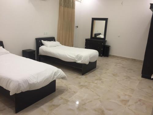 a hotel room with two beds and a mirror at Al Sondos Furnished Apartments in Abha