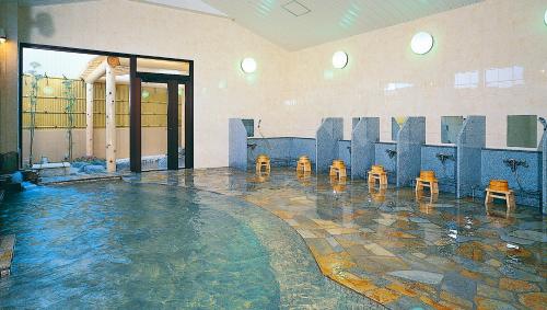 a swimming pool with four stools in a building at Hotel Hana Isawa in Fuefuki