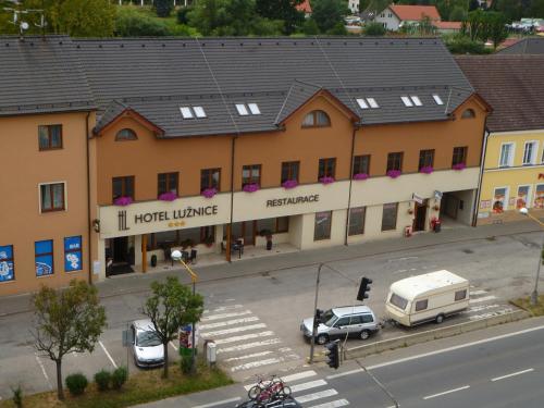 Planá nad Lužnicí的住宿－盧日尼采酒店，街上的一座建筑,停车场有车辆停放