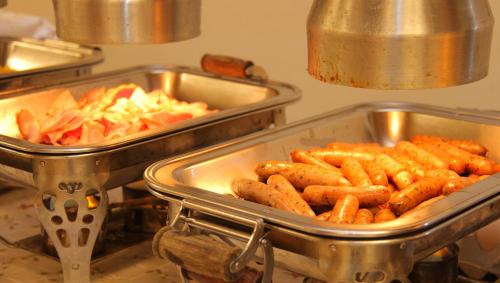 two metal trays of carrots and other food on a stove at Hotel Hana Isawa in Fuefuki