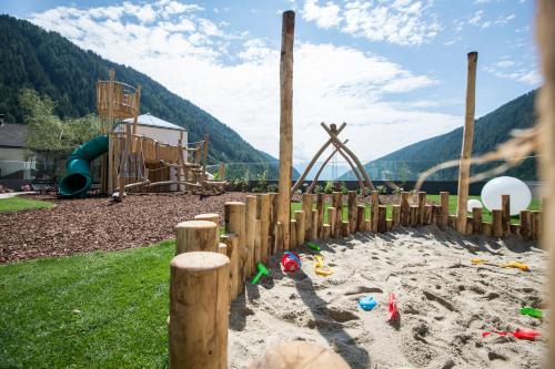 a childrens playground with a sandbox and a slide at Familienhotel Huber in Valles