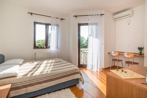a bedroom with a bed and a desk and two chairs at Apartments Vienna in Zambratija