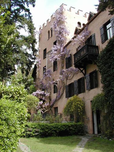 a building with a tree with purple flowers on it at Schloss-Castel Pienzenau - Guestrooms & Apartments - B&B-Hotel & Restaurant in Merano