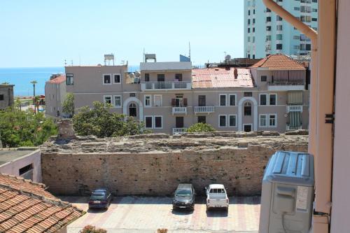 a group of cars parked in a parking lot next to a brick wall at Hotel Nais in Durrës
