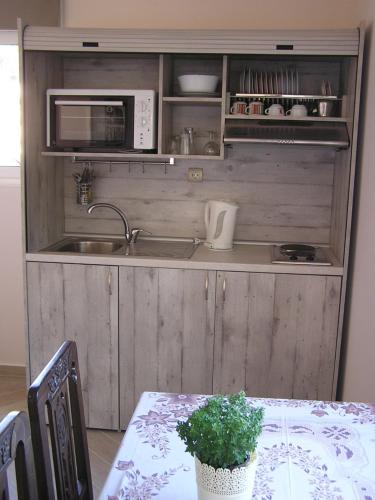 a kitchen with a table and a sink and a microwave at Eolos Apartments with Private Parking in Agios Nikitas
