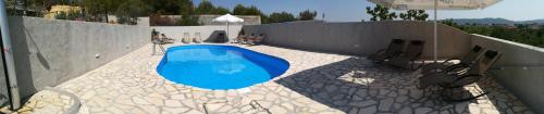 a swimming pool with chairs and an umbrella at Apartments T&C in Drage