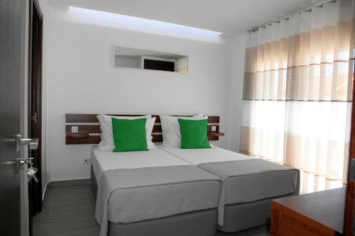 1 dormitorio con 1 cama grande con almohadas verdes en Baleal 4 Surf II, en Baleal