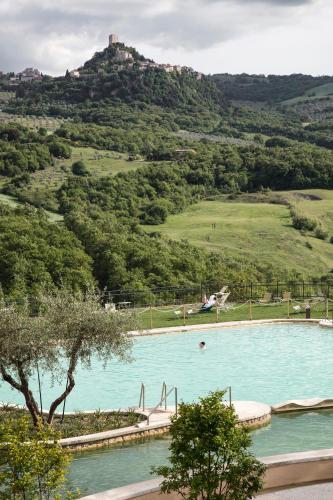 a large swimming pool with a hill in the background at La Posta Hotel & Thermal Spa in Bagno Vignoni