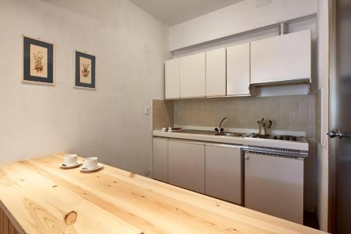 アラッバにあるAppartamenti Carlottaの白いキャビネットと木製テーブル付きのキッチン