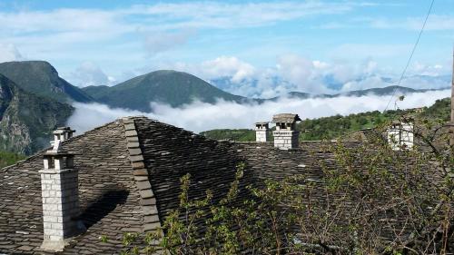 a roof of a building with mountains in the background at Traditional Rooms karaouli in Papigko
