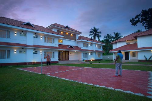 two people playing a game of baseball in front of a building at Le Coffee Resort in Sultan Bathery