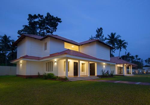 a large white house with the lights on at Le Coffee Resort in Sultan Bathery