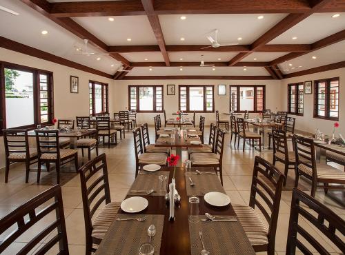 a dining room with wooden tables and chairs and windows at Le Coffee Resort in Sultan Bathery