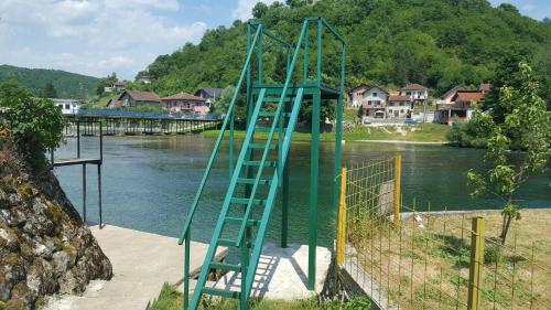 a green ladder sitting on the side of a river at Apartment Sajra in Kulen Vakuf
