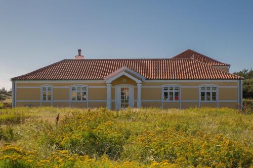 a yellow house with a red roof in a field at Hjorths Badehotel in Kandestederne