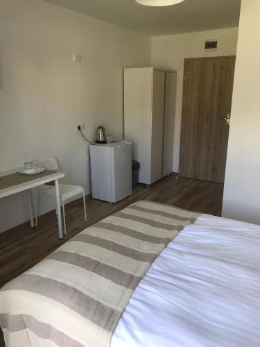 a bedroom with a bed and a table and a refrigerator at Willa Wena in Ustka