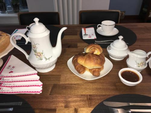 a table with a tea pot and a plate of croissants at B&B Vista su Roma in Marco Simone