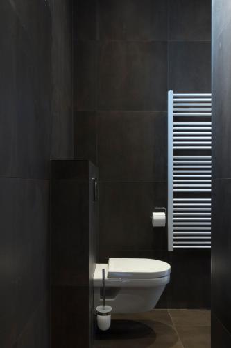 a bathroom with a white toilet in a black wall at 2L Hof van Holland apartments in Noordwijk