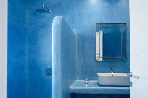 a blue bathroom with a sink and a mirror at Anemomilos in Oia