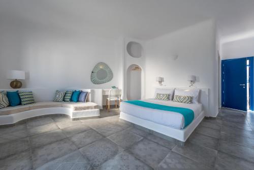 a white bedroom with a bed and a couch at Anemomilos in Oia