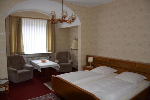 a bedroom with a bed and a chair and a window at Pension Cecilie in Braunlage