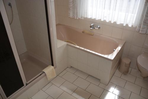 a bathroom with a bath tub and a toilet at Pension Cecilie in Braunlage
