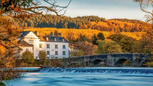 a bridge over a river in front of a building at The Swan Hotel and Spa in Newby Bridge