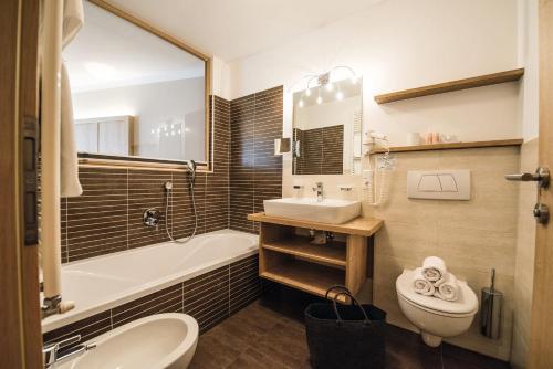 a bathroom with a sink and a tub and a toilet at Apartment Sella in Siusi