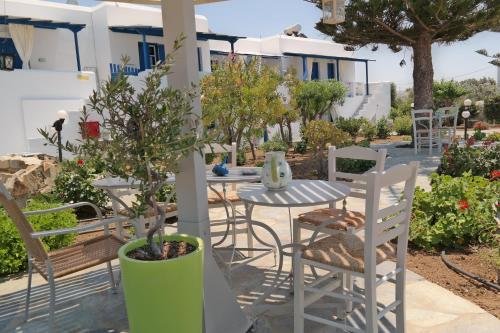 a patio with a table and chairs and trees at Maroussa Studios in Agia Anna Naxos