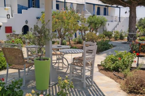 a patio with chairs and tables and trees at Maroussa Studios in Agia Anna Naxos