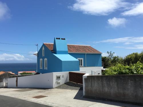 a blue and white house with the ocean in the background at Casa do Vizinho in Porto Judeu