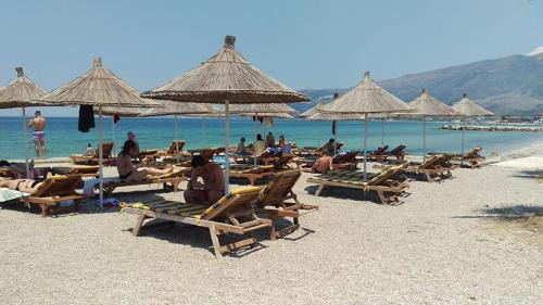 a group of people sitting on a beach with umbrellas at Sunrise Hotel Orikum in Orikum