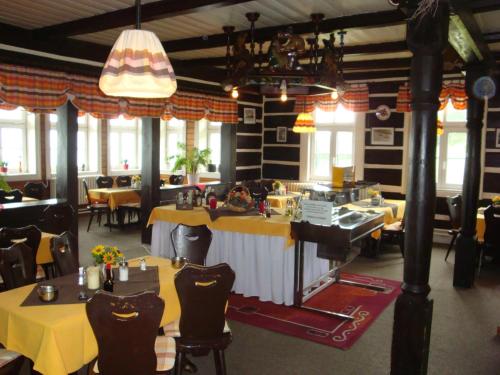 a restaurant with yellow tables and chairs and windows at Moravská Bouda in Špindlerův Mlýn