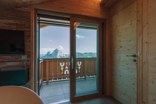 a room with a balcony with a view of a mountain at Caschu Alp Boutique Design Hotel Stoos - adults only in Stoos