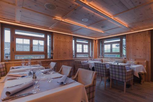 a restaurant with white tables and chairs and windows at Caschu Alp Boutique Design Hotel Stoos - adults only in Stoos