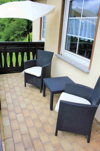 a patio with two chairs and an umbrella at Beilsteiner Gästehaus in Beilstein
