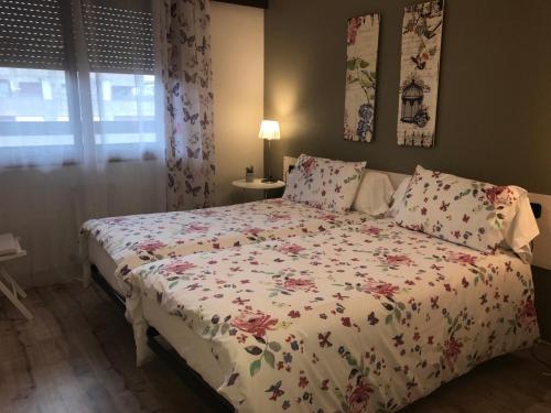 a bedroom with a bed with a floral bedspread at Alojamientos Olga in Pamplona