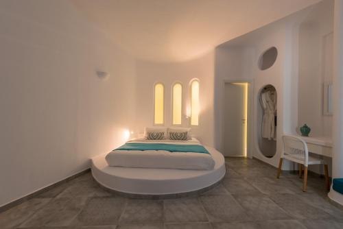 a bedroom with a bed in a room with a table at Anemomilos in Oia
