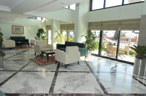 a lobby with white chairs and tables and windows at Bugday Hotel in Ankara
