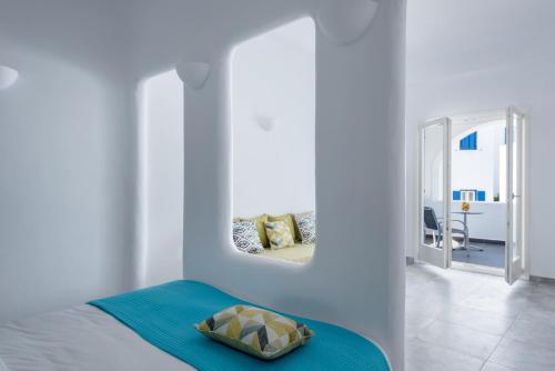 a white room with a bed and a mirror at Anemomilos in Oia
